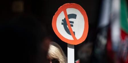 (FILES) A woman holds a placard with the symbol of Euro during a demonstration against Bulgaria entering the Eurozone in Sofia on June 4, 2025. Bulgaria will become the 21st country to adopt the euro on January 1, 2025, but some believe the move could bring higher prices and add to instability in the European Union's poorest country. A protest campaign emerged this year to 