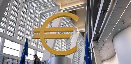 TOPSHOT - A man walks past the logo of the European Central Bank (ECB) at the central bank's headquarters in Frankfurt am Main, western Germany, on December 18, 2025, prior to the meeting on the Eurozone's monetary policy,. (Photo by Kirill KUDRYAVTSEV / AFP)