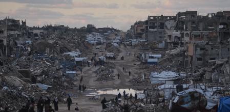 Palestinians walk past destroyed buildings in the northern Gaza Strip, Friday, Jan. 2, 2026. (AP Photo/Jehad Alshrafi)