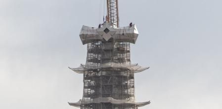 Los operarios, ajustando el brazo horizontal en el núcleo de la cruz