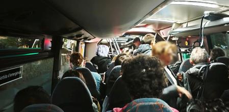 Pasajeros de pie en medio del pasillo del autobús mientras cirucla por la autopista .