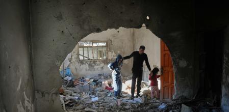 Un grupo de palestinos inspecciona bajo los escombros en Deir al-Balah, en el centro de la Franja