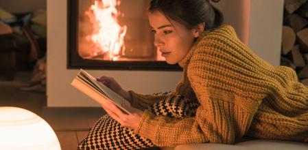 Una chica disfruta del placer de la lectura junto al fuego en invierno