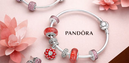 Pulseras Pandora con charms icónicos en tonos rosas y rojos, fotografía de producto sobre fondo floral