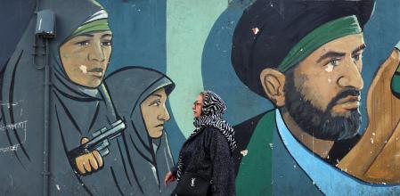 Un dona camina davant d’un mural amb soldats iranians en un carrer deTeheran