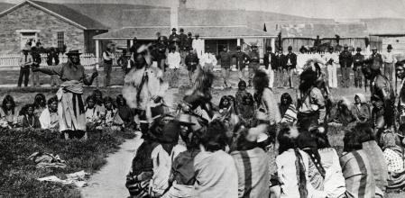 A group Shoshoni dance at the Fort Washakie reservation in Wyoming. Standing at far left, with his arm outstretched, is Chief Washakie.