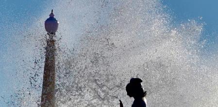 Jesús Marimon muestra cómo la escultura de La Sirena, obra de Pere Jou, planta caraal oleaje desde el espigón de la Punta, bajo la iglesia de Sitges, durante el