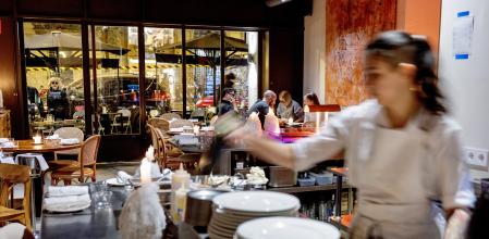 La barra de metal con la luz de las velas y el equipo en pleno movimiento y al fondo las mesas