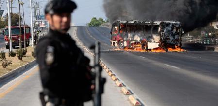 Un oficial de la Fiscalía mexicana junto a un bus incendiado en Zapopán, Jalisco, este domingo