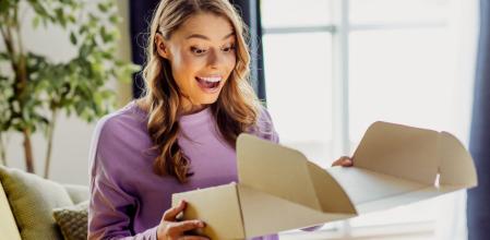 Una mujer sonríe encantada tras comprar un producto de Amazon a un precio increíble