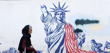 Una mujer camina junto a un mural antiestadounidense en Teherán.&nbsp;