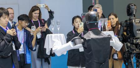 Equilibrio.Un robot sostiene sendas bandejas con copas llenas mientras sube y baja sin que su carga apenas se mueva.