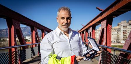 Miquel Bort sostiene la medalla en Tortosa, sobre el río Ebro, tras 26 años de charlas y formaciones