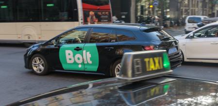 Un coche VTC que opera a través de la aplicación de Bolt y un taxi de toda la vida en el centro de Barcelona