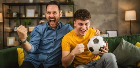 Padre e hijo viendo un partido de fútbol en el televisor