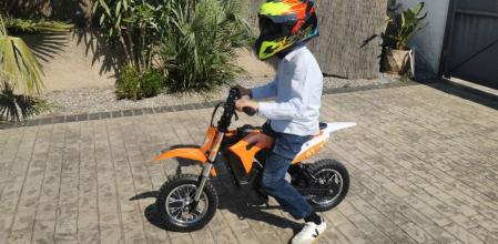 Mi sobrino muy contento con su bicicleta eléctrica en el jardín de su casa