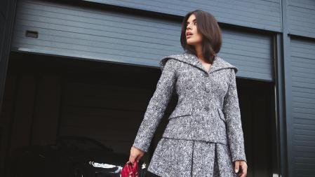 Dulceida viste una falda corta, tableada, combinada con chaqueta de lana jaspeada de Dior con bolso micro Lady Dior en rojo