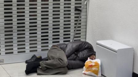 Un mendigo se acomoda en el cajero automático de una entidad bancaria de la zona alta de la ciudad para pasar la noche