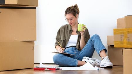 Shot of pretty young woman writing inventory of her belongings of her new house while sitting on the floor at home. (Shot of pretty young woman writing inventory of her belongings of her new house while sitting on the floor at home., ASCII, 116 compon