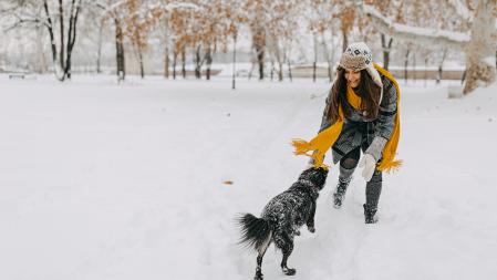 Young woman playing with dog in the snow