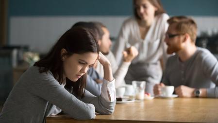 Upset young girl sit alone at coffee table in cafe feeling lonely or offended, sad female loner avoid talking to people, student outsider suffer from discrimination, lacking friends or company (Upset young girl sit alone at coffee table in cafe feel