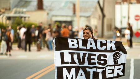 A protester carries a Black Lives Matter flag shortly before the start of a dawn to dusk curfew following the killing of Andrew Brown Jr. by sheriffs last week, in Elizabeth City, North Carolina, U.S. April 27, 2021. REUTERS/Jonathan Drake