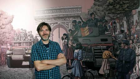 El dibujante valenciano Paco Roca posa junto al mural que aparece en su libro 'Los surcos del azar'