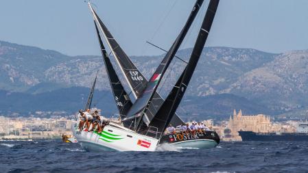 Dos de los veleros participantes en la Copa del Rey Mapfre 2021 se cruzan navegando en ceñida en la bahía con la catedral de Palma al fondo