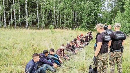 Polish border patrol officers detain people attempting to cross the border between Belarus and Poland, in this handout picture released on August 9, 2021. Main Command of the Polish Border Patrol/Handout via REUTERS THIS IMAGE HAS BEEN SUPPLIED BY A THIRD PARTY. MANDATORY CREDIT. NO RESALES. NO ARCHIVES. PIXELLATION FROM SOURCE