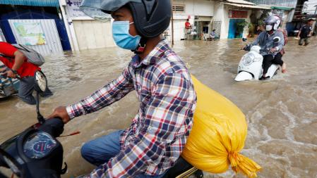 Phnom Penh (Cambodia), 28/10/2021.- People ride their motorbikes in a flooded street at a village on the outskirts of Phnom Penh, Cambodia, 28 October 2021. Thousands of people along Stung Prek Tnaot river in Phnom Penh have been affected by rising flood waters as Cambodia's Ministry of Water Resources issued flood warnings across the country from 27 Oct to 02 November. (Inundaciones, Camboya, Estados Unidos) EFE/EPA/MAK REMISSA