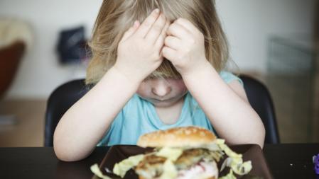 Una niña ante su plato de comida