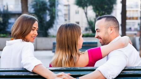Un trío poliamoroso disfruta en un banco de un parque
