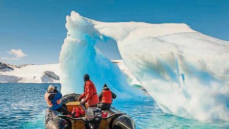 Un grupo de turistas contemplan un iceberg en la Antártida