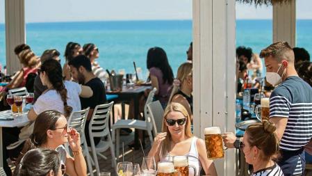AMBIENTE DE PLAYA EN LA BARCELONETA EN EL SÁBADO DE SEMANA SANTA. UN GRUPO DE TURISTAS BEBIENDO JARRA DE CERVEZA EN UN CHIRINGUITO JUNTO A LA PLAYA