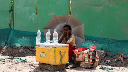 Una chica vende agua bajo la sombra de un paraguas en Nueva Delhi