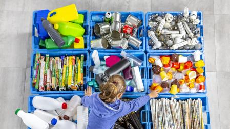 Garbage bins for recycling. A girl is using them.