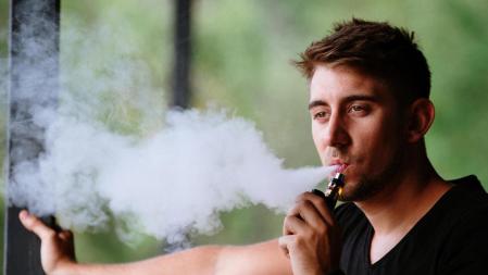 Un joven vapeando con un cigarrillo electrónico