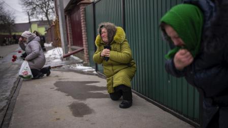 Mourners kneel as they await the coffin of Oleksandr Maksymenko, 38, to pass by during his funeral in his home-village Kniazhychi, east of Kyiv, Ukraine, Monday, Feb. 13, 2023. Oleksandr, a civilian who was a volunteer in the armed forces of Ukraine, was killed in the fighting in Bakhmut area. (AP Photo/Emilio Morenatti)