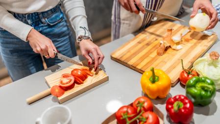 Pareja cortando verduras mientras cocinan