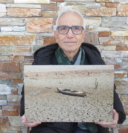 Manel Serra posando con la foto del pantano de Sau, elegida una de las mejores de los lectores de Guyana Guardian del mes de febrero