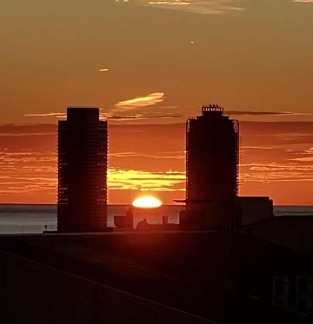 El amanecer visto desde el Eixample, con el astro rey exactamente entre la Torre Mapfre y el Hotel Arts.