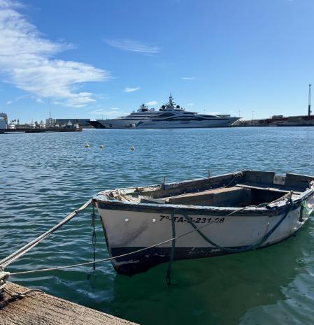 Una barca muy modesta de algún pescador frente a los megayates de millonarios, en el puerto de Tarragona.