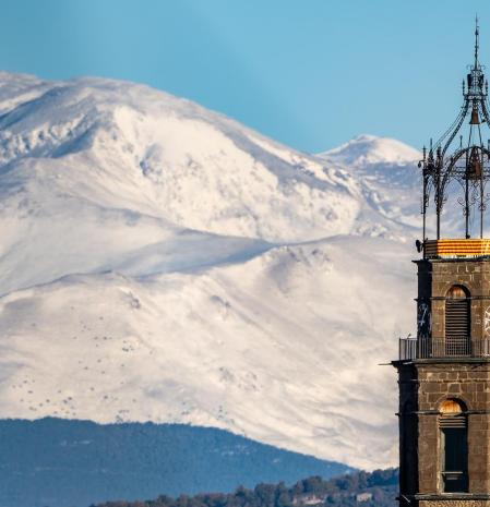 El campanario de la iglesia de Manlleu con el Pirineo nevado de fondo.