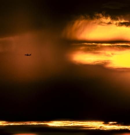 Fotografía de un avión surcando el cielo del amanecer.