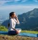 Un mujer practica la respiración controlada pranayama, en la posición del loto, por la mañana, con las montañas del Himalaya al fondo