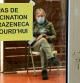 A man waits in a vaccination center where a sign reads 