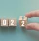 Hand flipping over wooden block of 2021 to 2022, New Year Resolutions, business concept