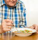 Un anciano comiendo verduras