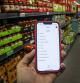 Un consumidor consulta la lista de la compra confeccionada en un smparthone mientras visita un supermercado