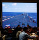 Customers dine near a giant screen broadcasting news footage of an aircraft taking off from China's Shandong aircraft carrier while taking part in a combat readiness patrol and 